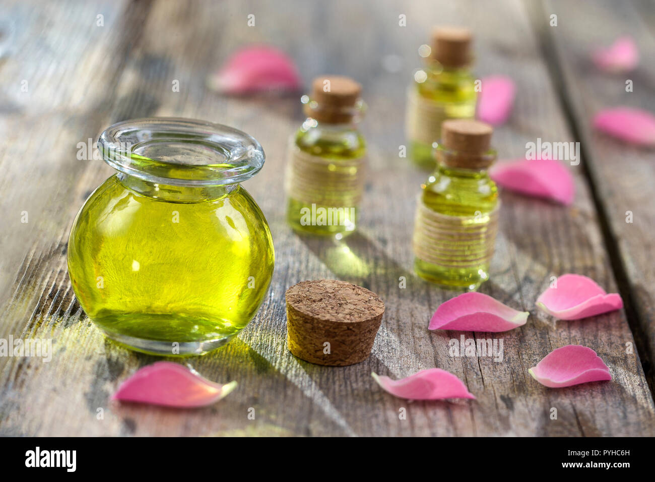 Rose flower petals with aromatherapy essential oil glass bottle isolated over wooden, background, copy-space Stock Photo