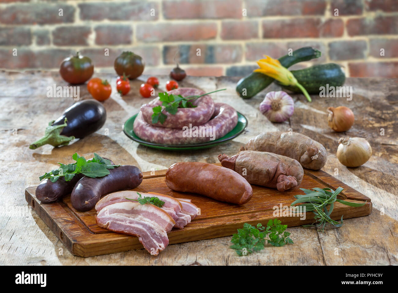 Selection of French Raw sausage with arugula leaves in a wooden board,vegetable on the table on old red brick background. Stock Photo