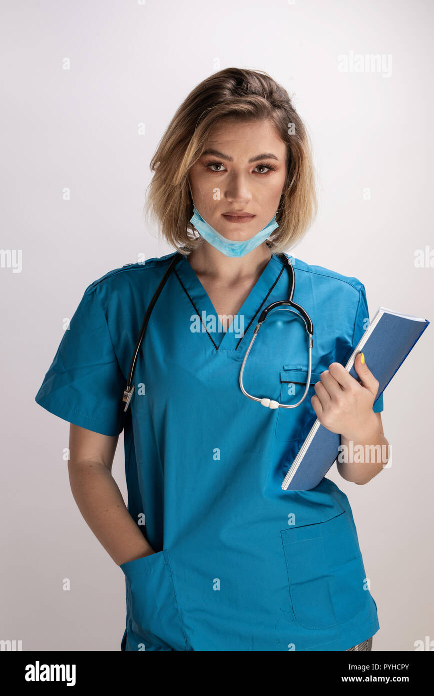 Portrait of young doctor with stethoscope holding paper results and standing straight with right hand in her pocket. Healthcare practicttioner specialist Stock Photo