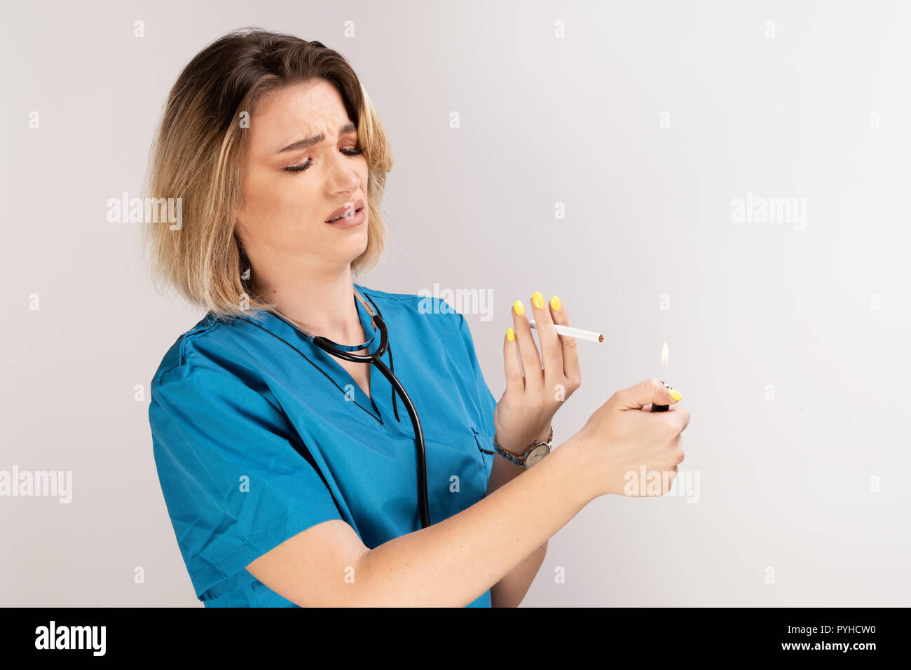Female doctor with stethoscope, cigarette and lighter looking negative on smoking. Smooking is a bad habbit for health Stock Photo