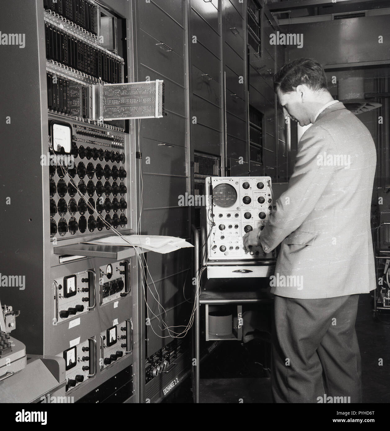 1960s, historical, a male technician working with stacks of broadcast equipment, including electronic oscillators. Stock Photo