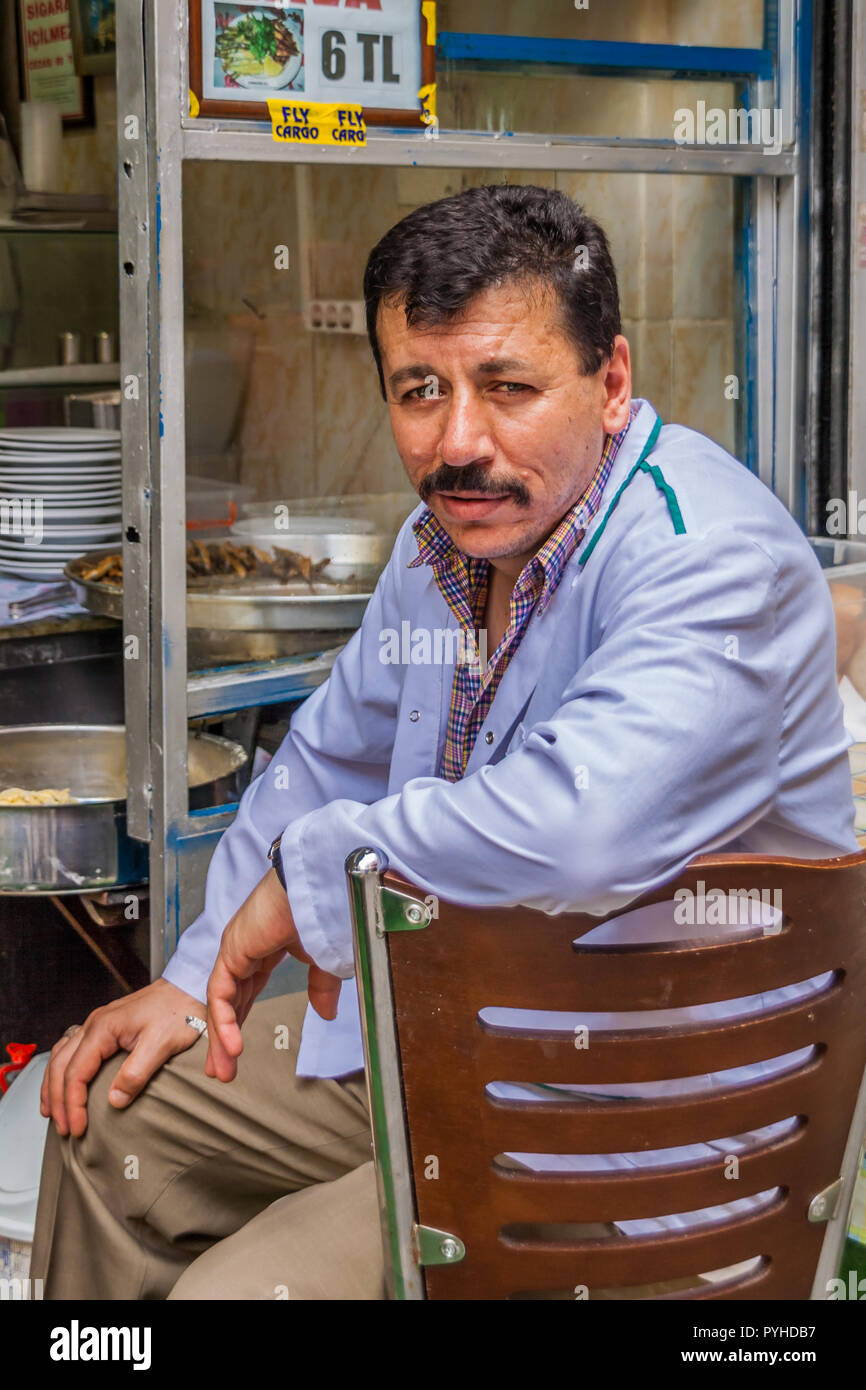 Man sitting and waiting outside his small restaurant in Istanbul. Stock Photo
