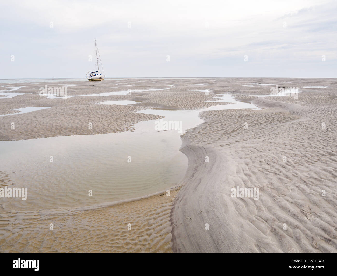 Sailboat dried out on sand flats of tidal sea Waddensea near Boschplaat, Terschelling, Netherlands Stock Photo