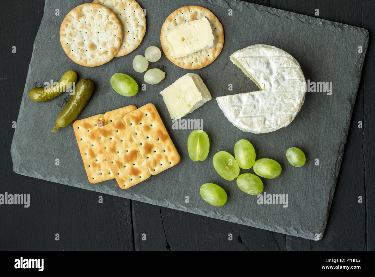 Camembert cheese and slices on water crackers with dill pickles and