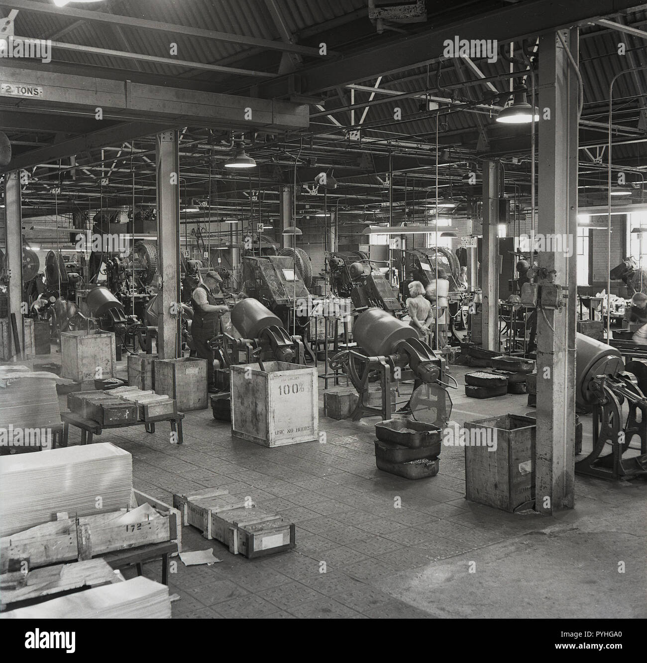 1950s, historical, male and fenale workers at the Ever Ready factory in Forest Road, Walthamstow, London overseeing the machinery producing parts - dry cells - for radio batteries and torches. The British Ever Ready Electrical Company ( BEREC) was one of the largest British companies of the era and by the early '60s had 28 factorires across Britain, quite a leap from its start in bueinss as a single shop in Charing Cross Rd. Stock Photo