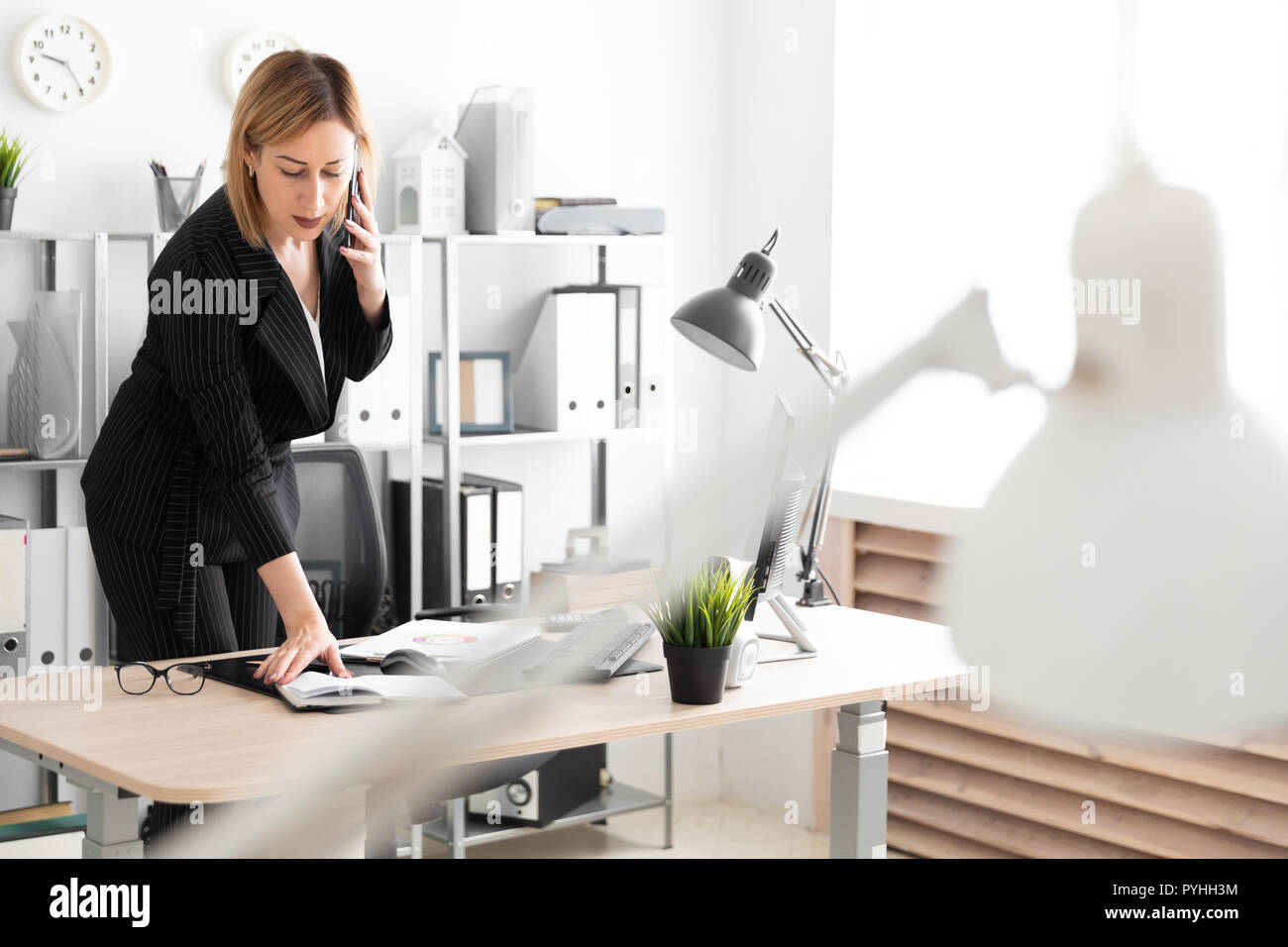 A Young Girl In The Office Talking On The Phone And Bent Over The