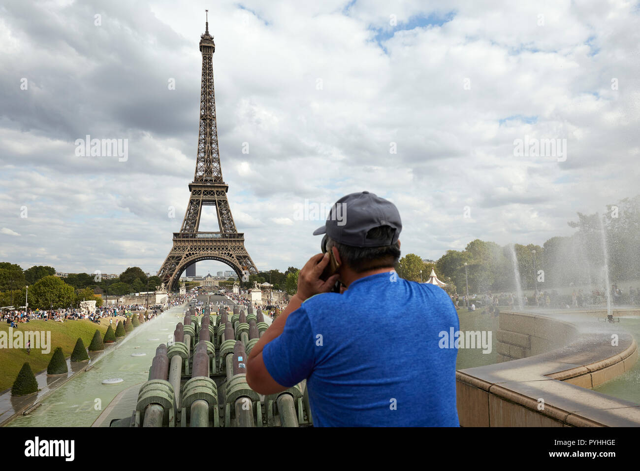 Paris, Ile-de-France, France - A man with a mobile phone on his left ear stands above the fountain in the Jardins du Trocadéro with the Eiffel Tower in the background. Stock Photo