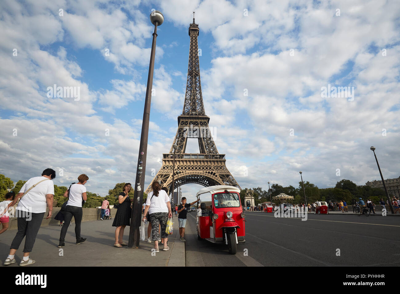 Paris, Ile-de-France, France - tourists stand at an autorickshaw on the Pont d'Iéna bridge, in the background the Eiffel Tower - the main landmark of the French capital. Stock Photo