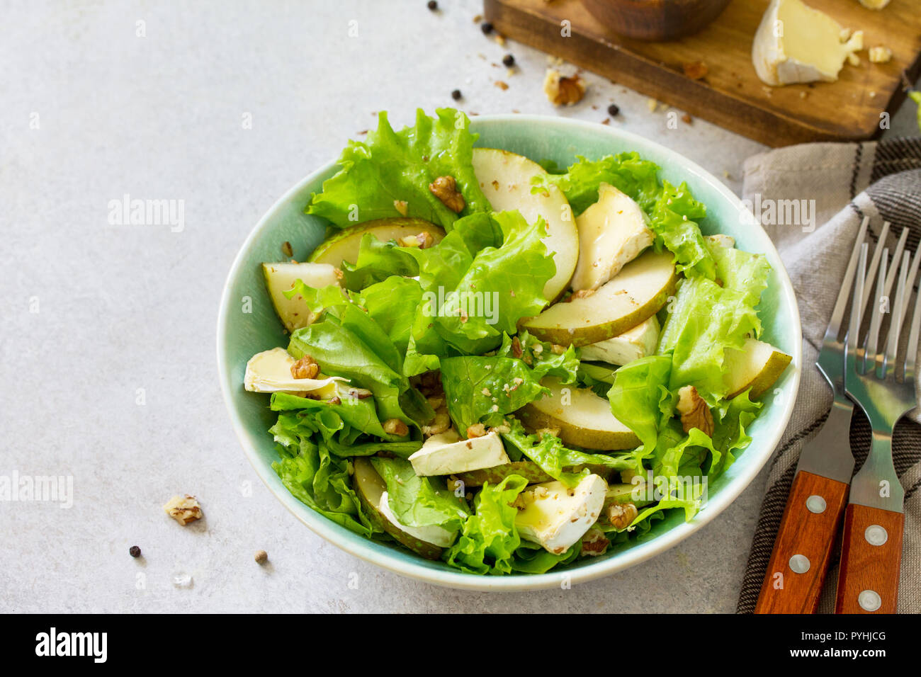 Pear Salad, Walnut, Camembert Cheese and Vinaigrette Dressing on stone table. Traditional french cuisine. Copy space. Stock Photo