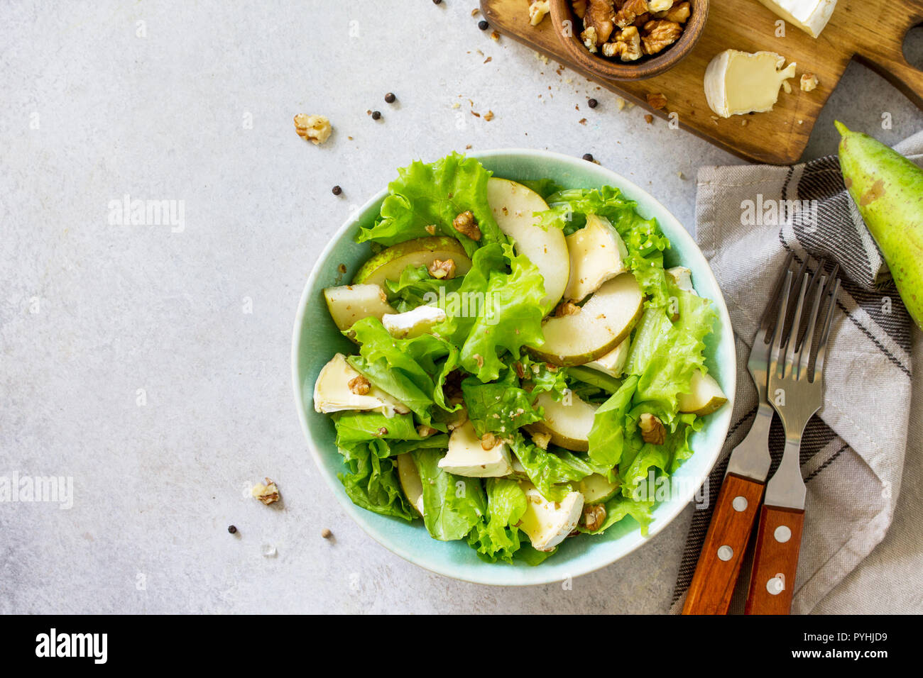 Pear Salad, Walnut, Camembert Cheese and Vinaigrette Dressing on stone table. Traditional french cuisine. Traditional french cuisine. Top view flat la Stock Photo