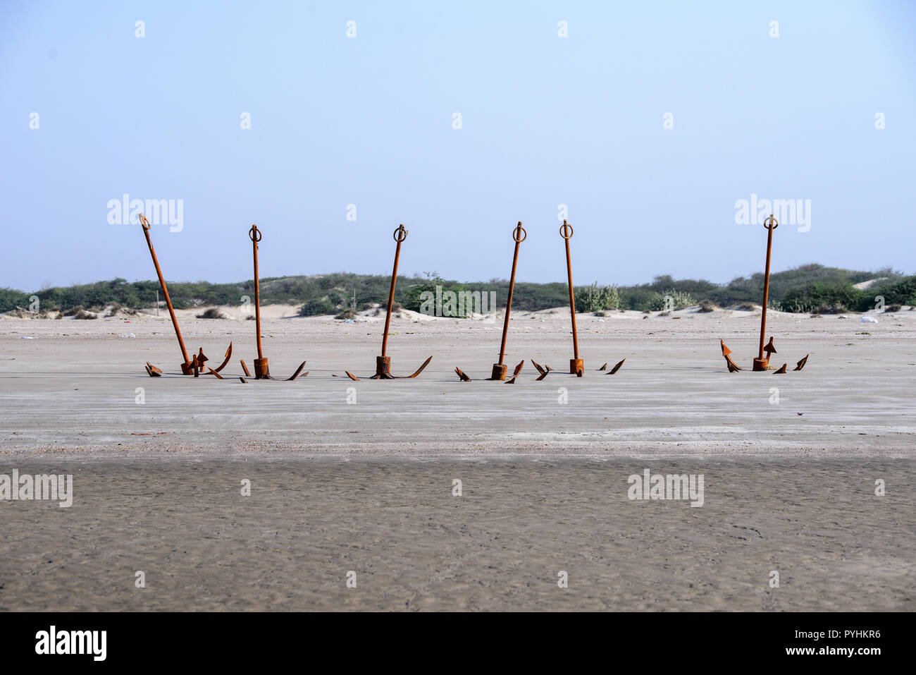 Rusty old anchors on the beach at low tide Stock Photo