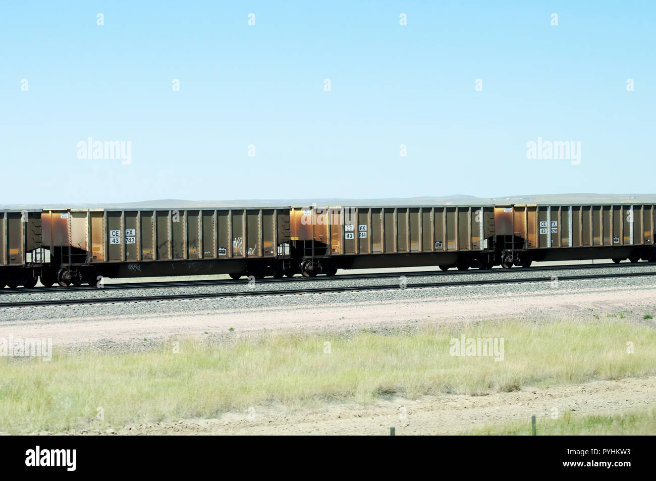 A long orange train traveling through the praire. Stock Photo