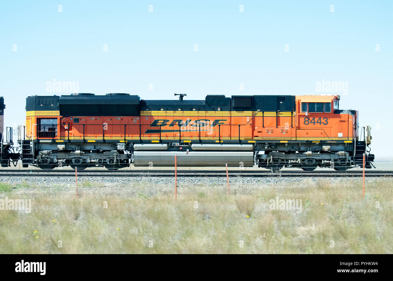 A long orange train traveling through the praire. Stock Photo