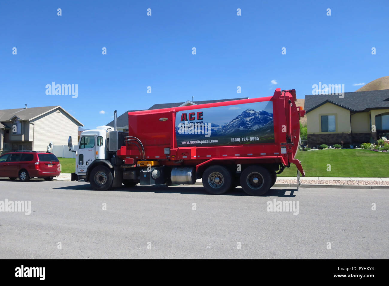 An automatic arm garbage truck picking up trash at the curb. Stock Photo