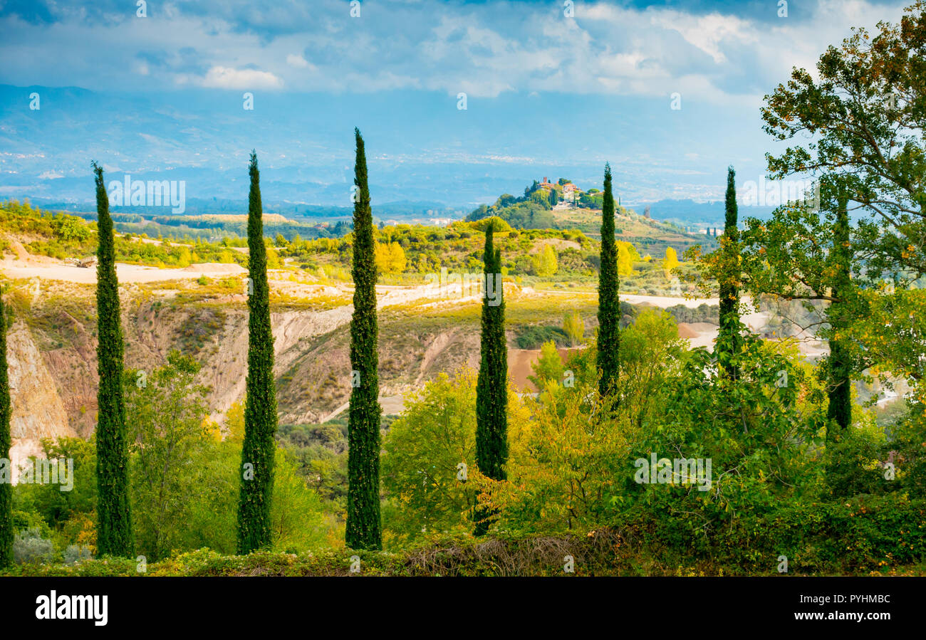 A row of cypresses framing Montaio di Cavriglia and Valdarno in autumn, Tuscany, Italy Stock Photo