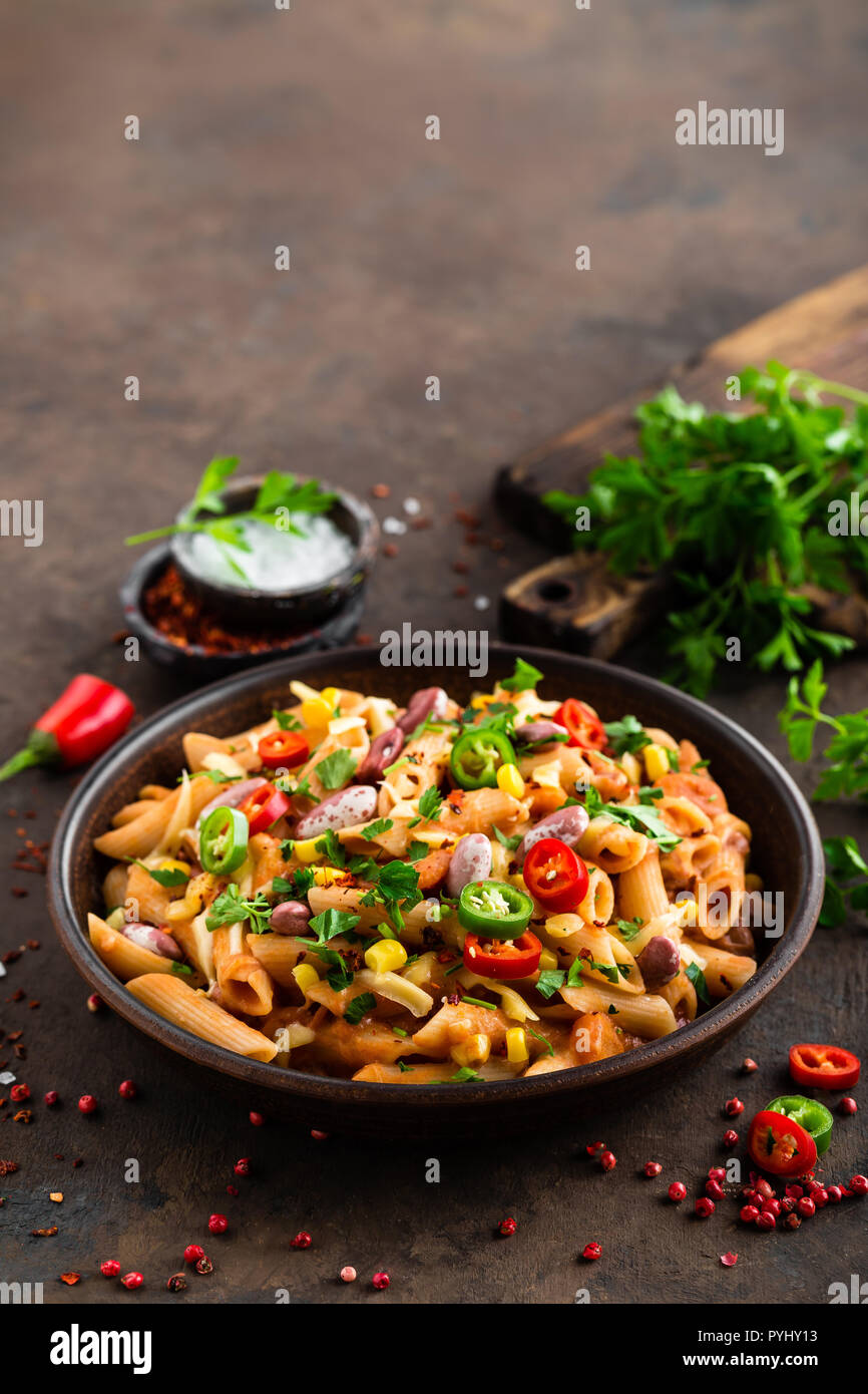 Spicy pasta penne bolognese with vegetables, beans, chili and cheese in