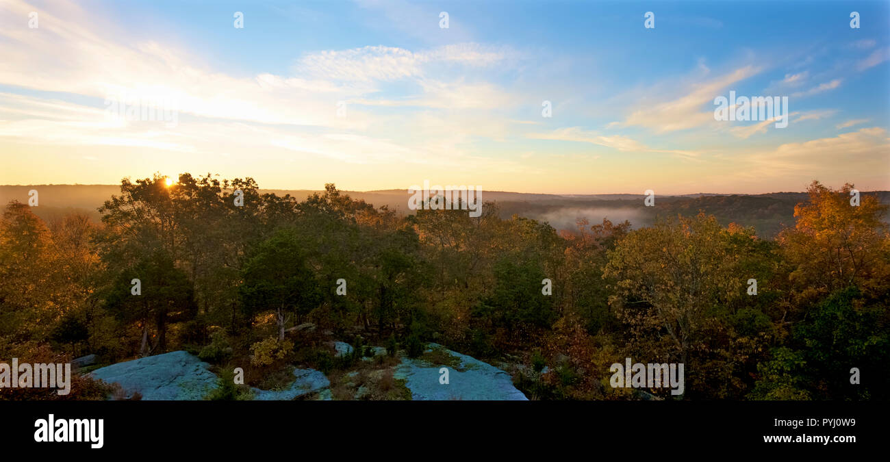 Panorama of sunrise over New England forest in fall color with blue sky and early morning fog Stock Photo