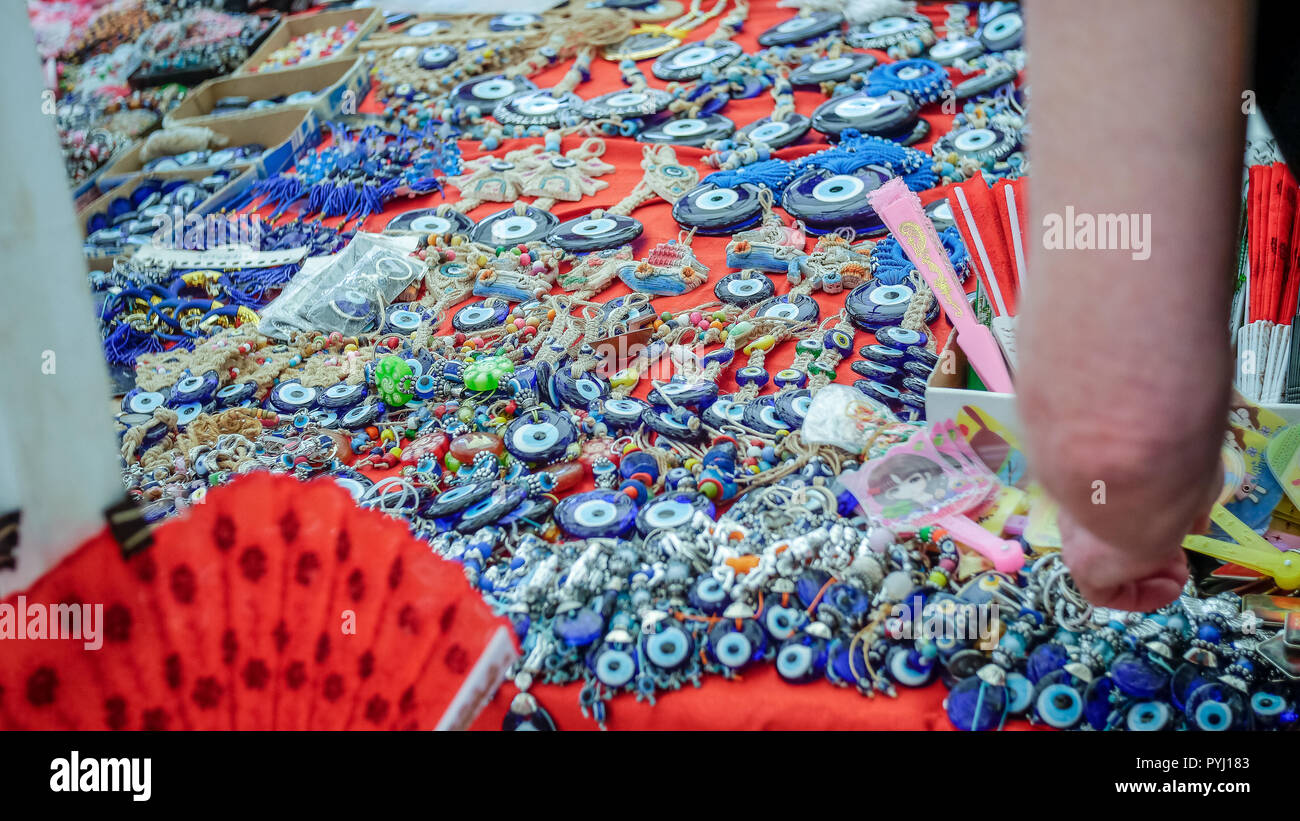 Ladies arm selecting Turkish Trinkets such as eyes of pottery at Turkey Market Stock Photo