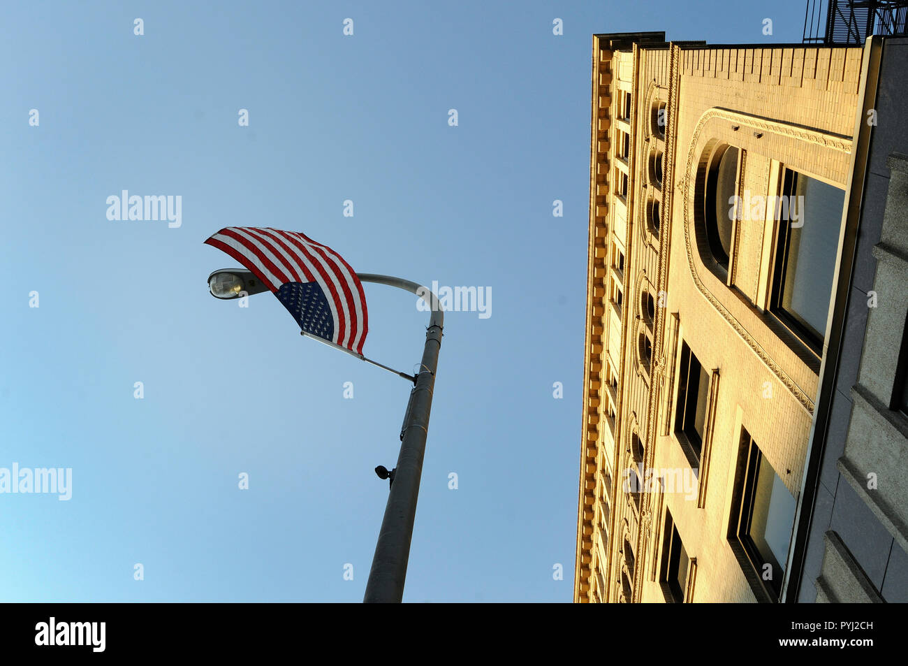 An American flag hangs upside down from a light standard on a city street. Stock Photo