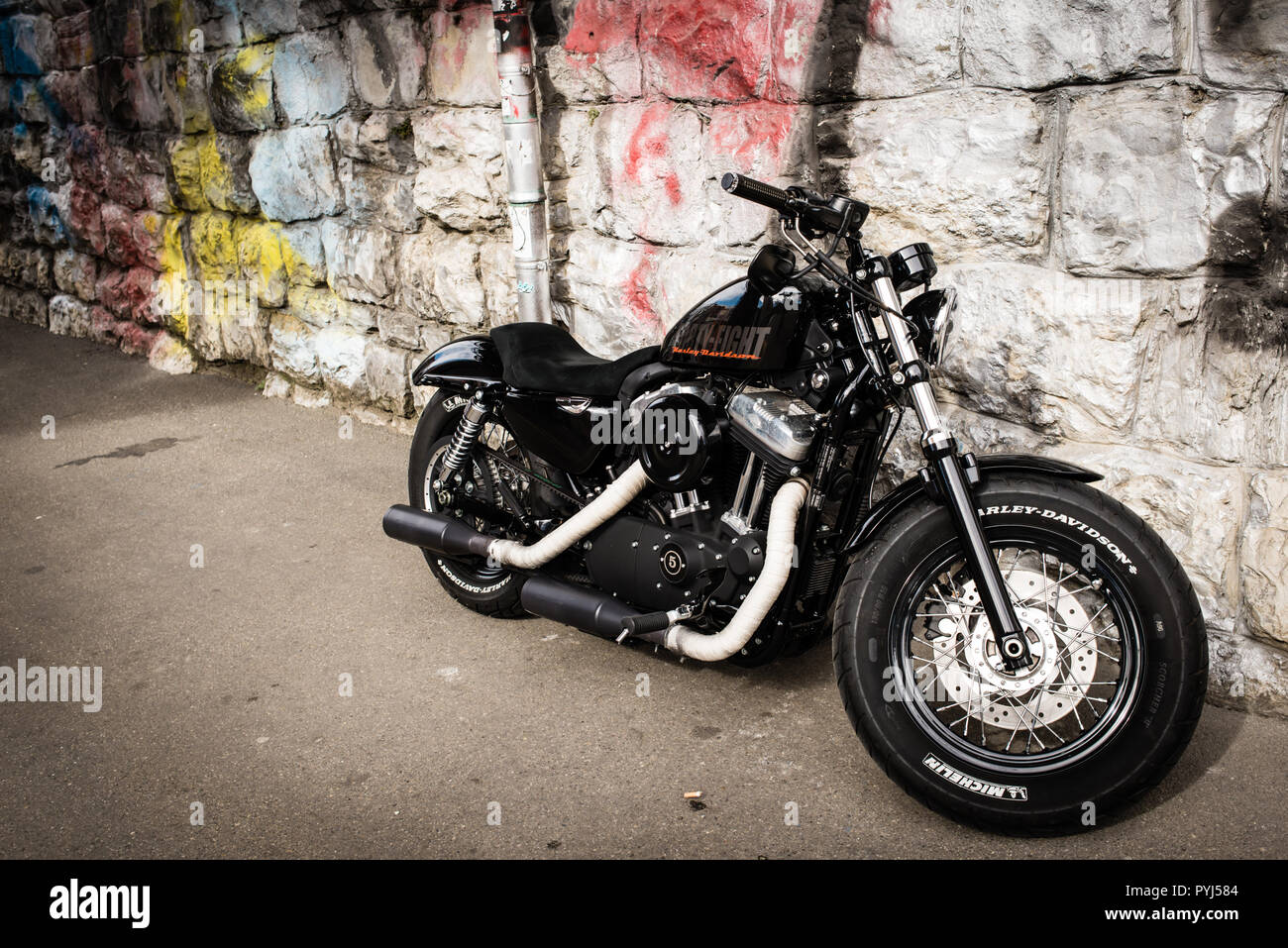 Zurich, Switzerland - March 2017: Black motorcycle 2017 Sportster Forty-Eight, motorbike Harley-Davidson with stone wall and graffiti in background Stock Photo