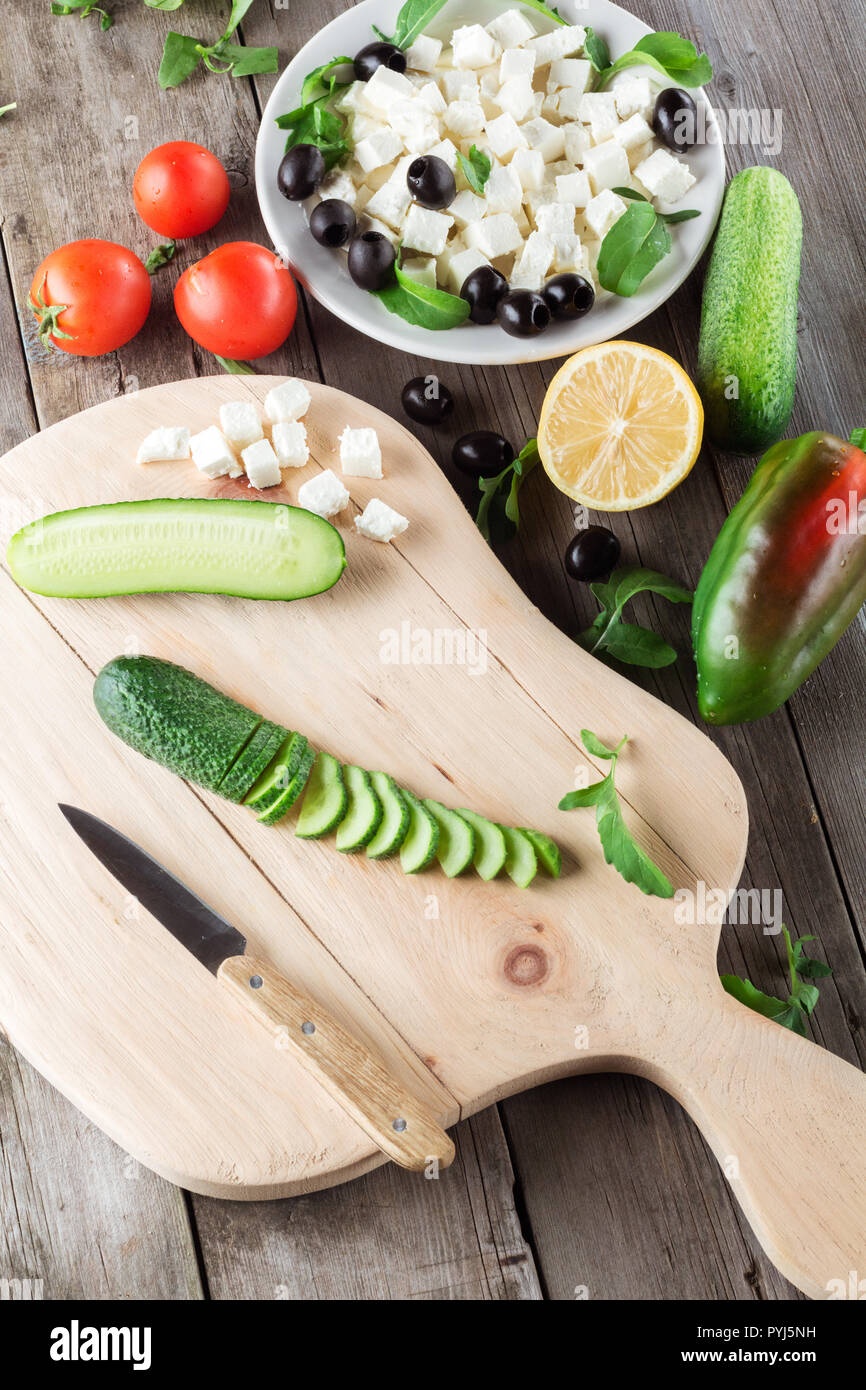 Cooking Greek salad, cutting a cucumber Stock Photo