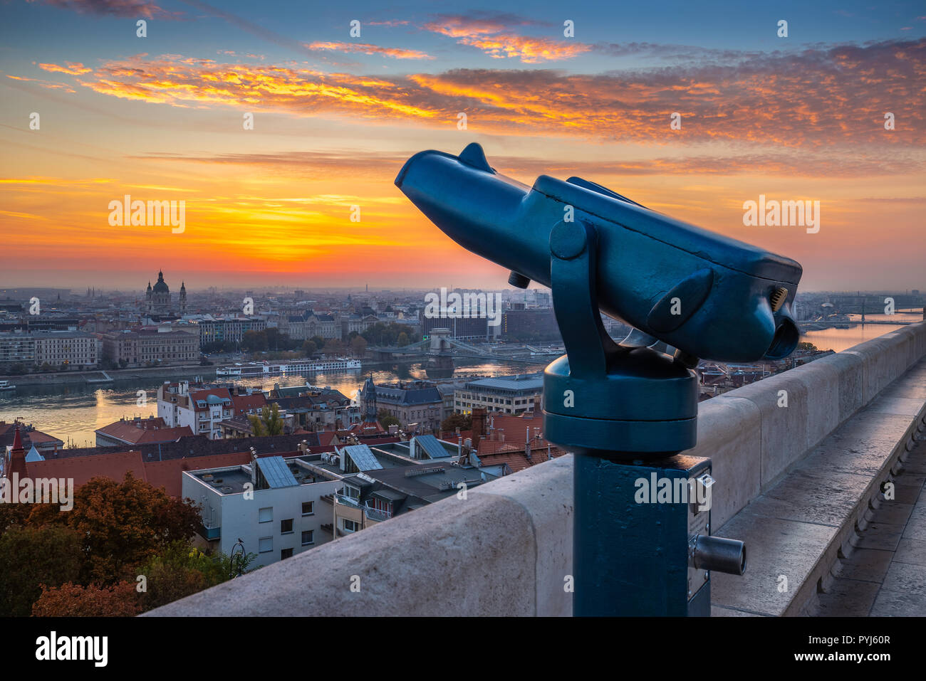Budapest, Hungary - Blue binoculars with the view of Pest with St. Stephen's Basilica, Szechenyi Chain Bridge and beautiful sky and clouds at sunrise Stock Photo