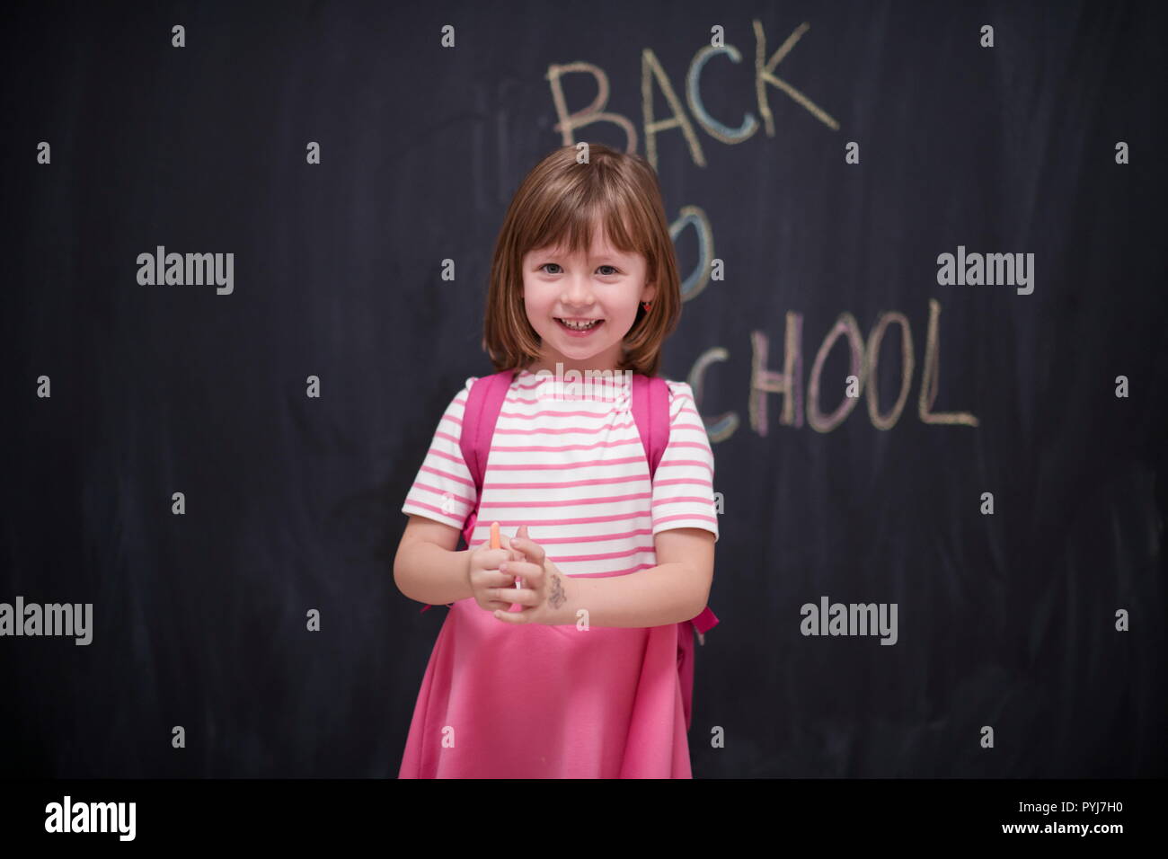 Happy school girl child with backpack writing back to school on black ...