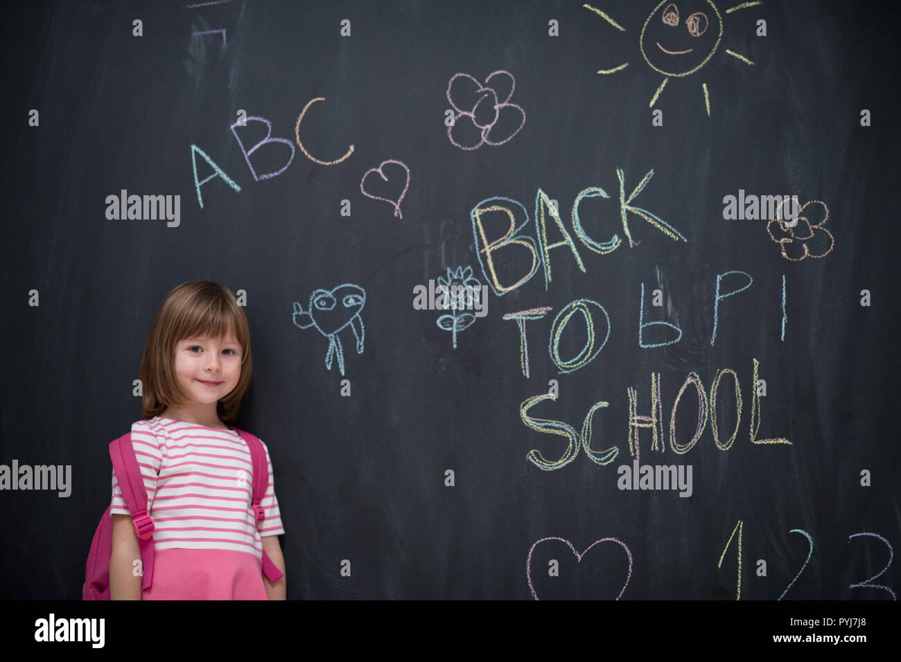 Happy school girl child with backpack writing back to school on black ...