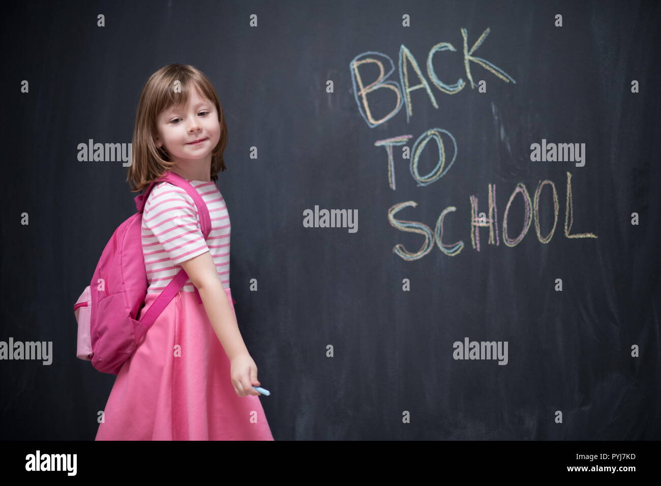 Happy school girl child with backpack writing back to school on black ...