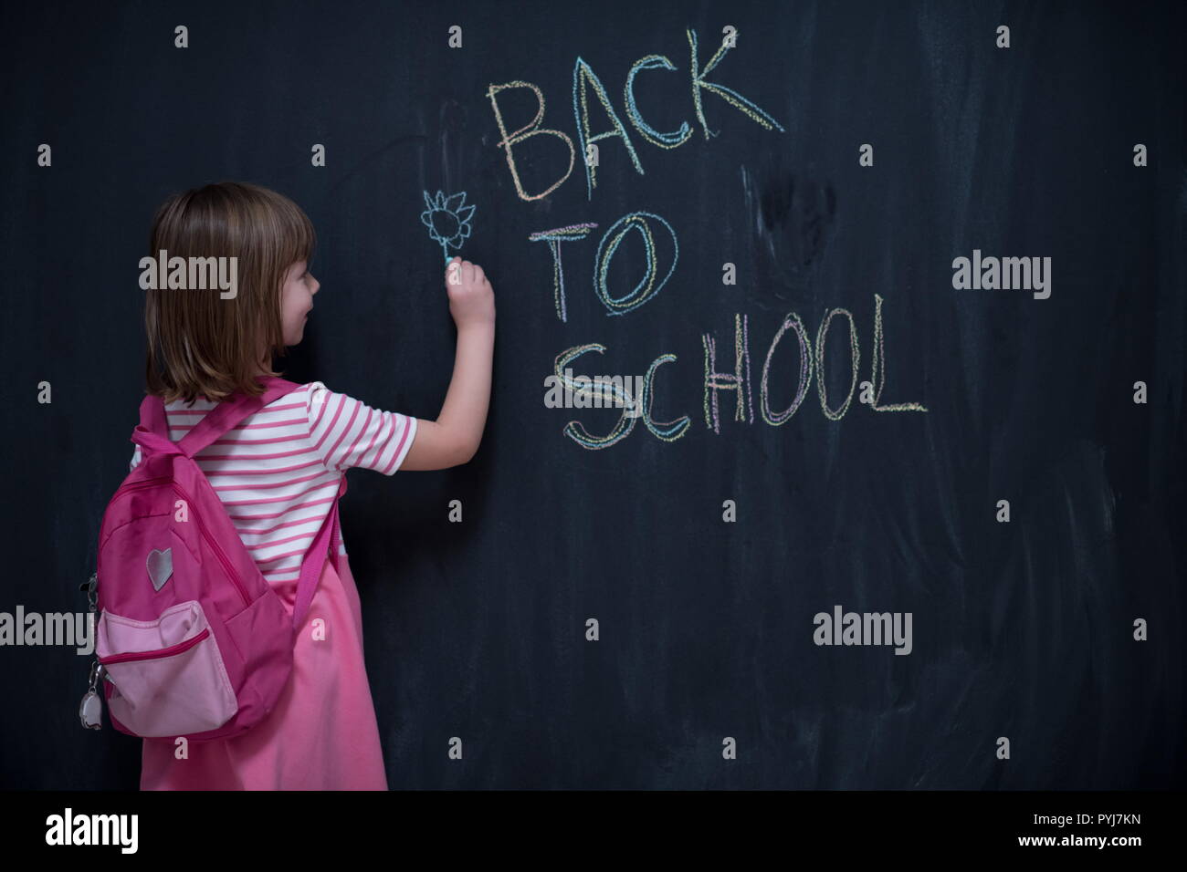 Happy school girl child with backpack writing back to school on black ...