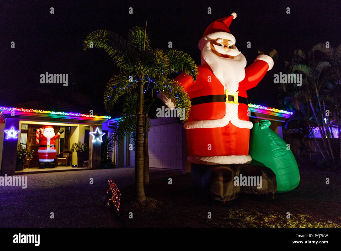 Big inflatable Santa Claus at CHRISTMAS LIGHTS festival in Queensland, Australia. House with  Christmas characters and fairy lights in the evening. Stock Photo