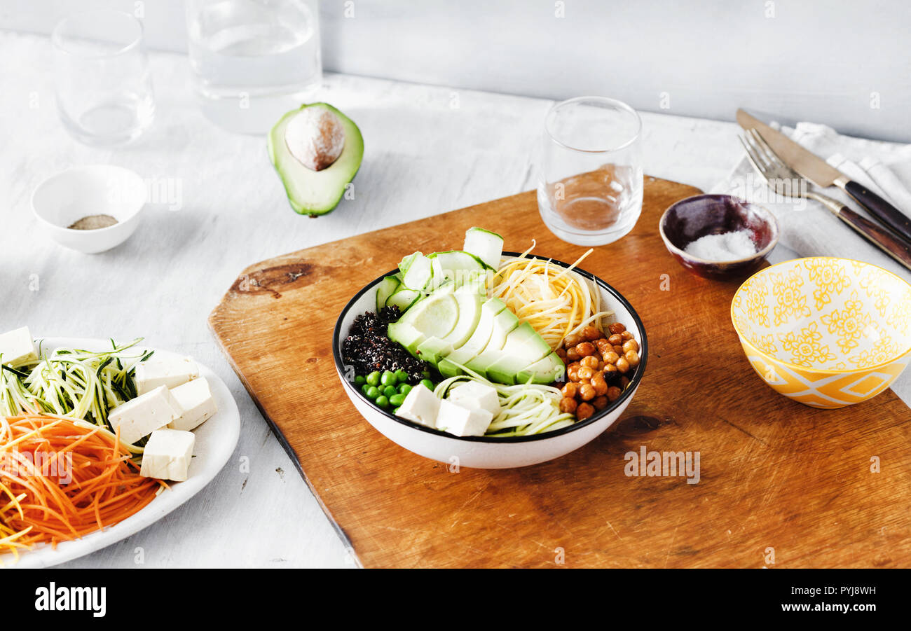 Set ingredients for cooking buddha bowl on wooden table. Quinoa, chickpea, tofu, cheese, zucchini, avocado, cucumber, spiralized vegetables Stock Photo