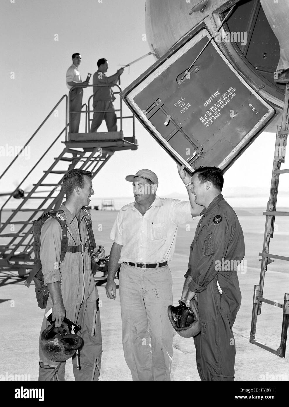 B-47A Stratojet on ramp with pilots and crew.  In 1954 after a research flight in the Boeing B-47A Stratojet Crew Chief Wilbur McClenaghan (center) asks of the pilots if there are any 'squawks' that should be taken care of before the next flight. Pilots are Joe Walker on the viewer's left and Stanley Butchart on the right. Data system technician Merle Curtis, in coveralls, is busy checking the airdata head mounted on the nose boom with the help of Instrumentation Crew Chief Raymond Langley.   The door to the cockpit area is open showing a view of the ladder that folds down to be used by the pi Stock Photo