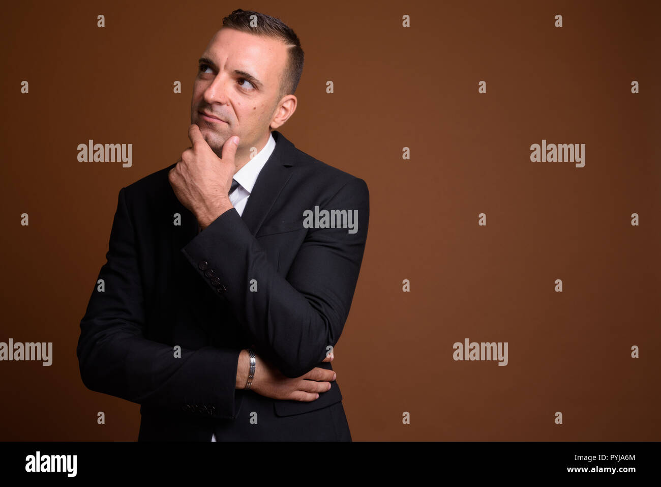 Portrait of businessman wearing suit against brown background Stock ...