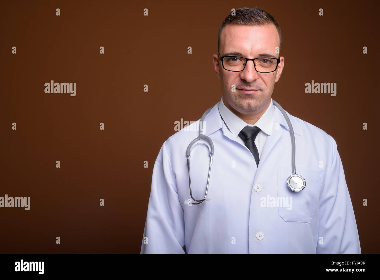 Man doctor wearing eyeglasses against brown background Stock Photo