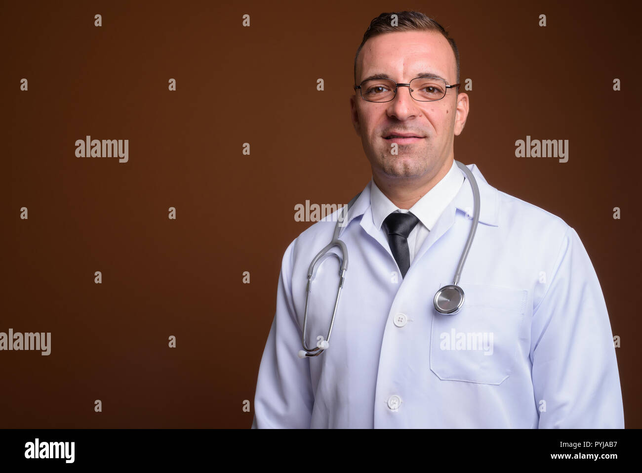 Man doctor wearing eyeglasses against brown background Stock Photo