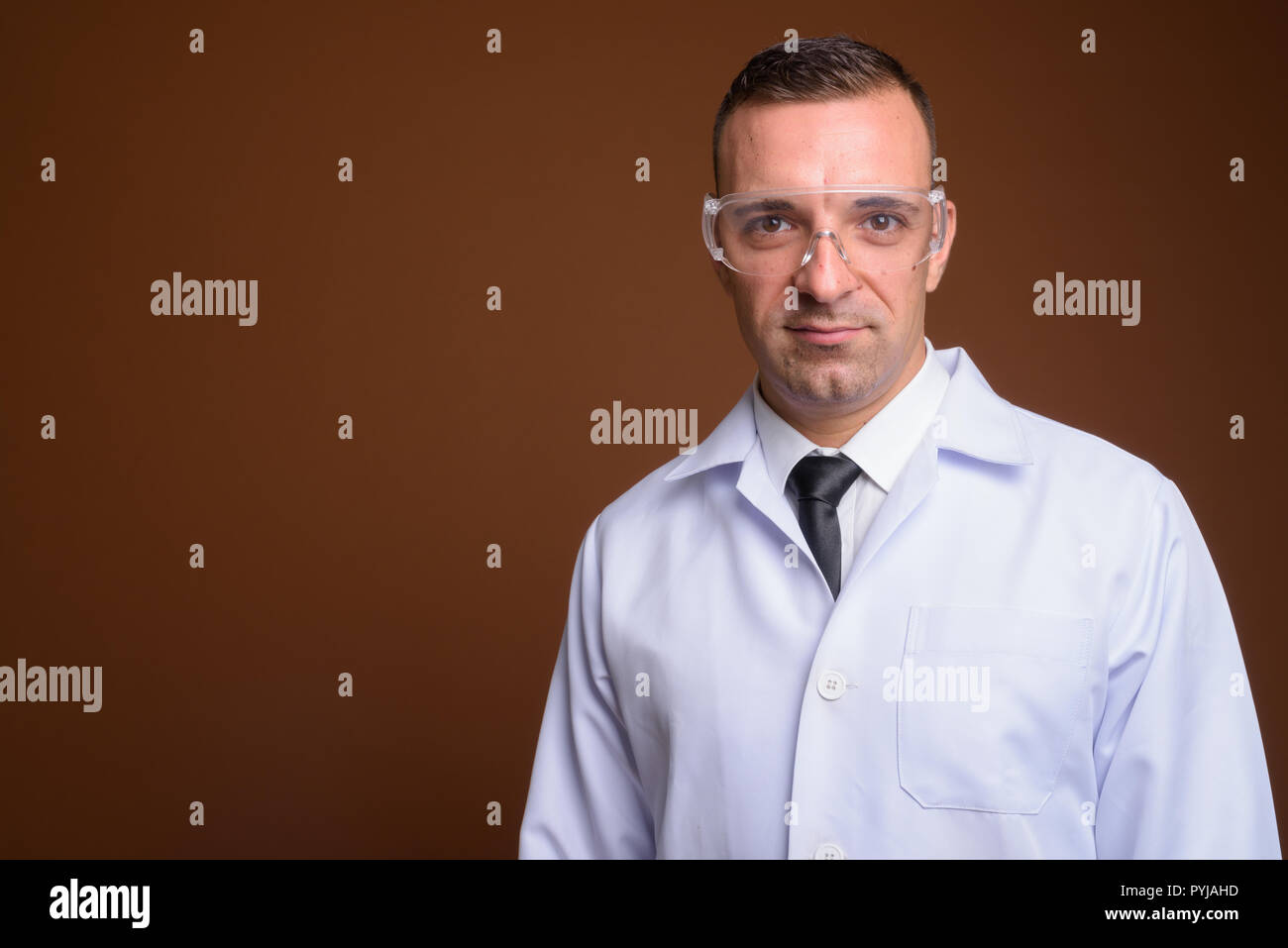 Man doctor wearing protective glasses against brown background Stock Photo