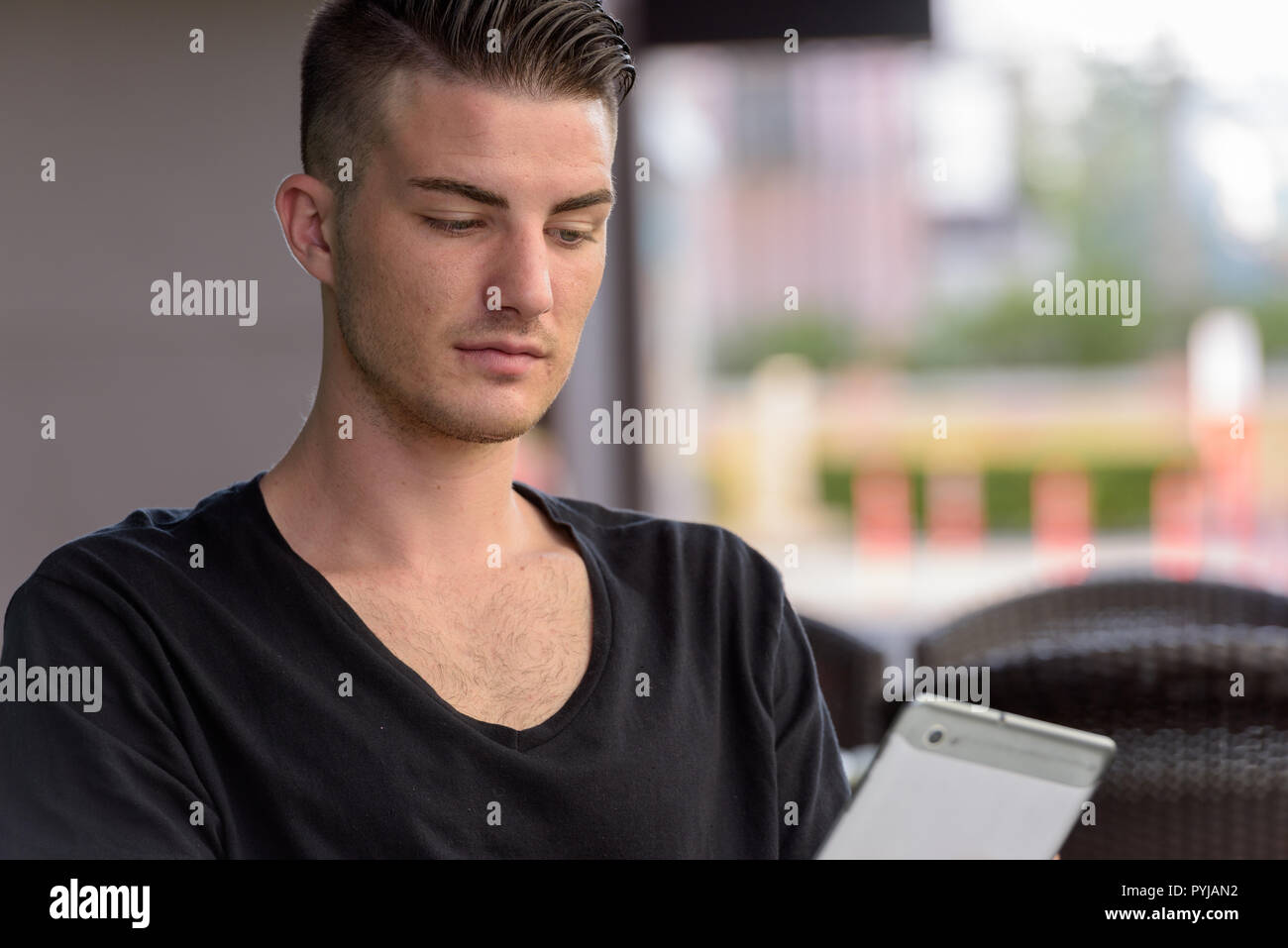 Young man using digital tablet outdoors while sitting Stock Photo