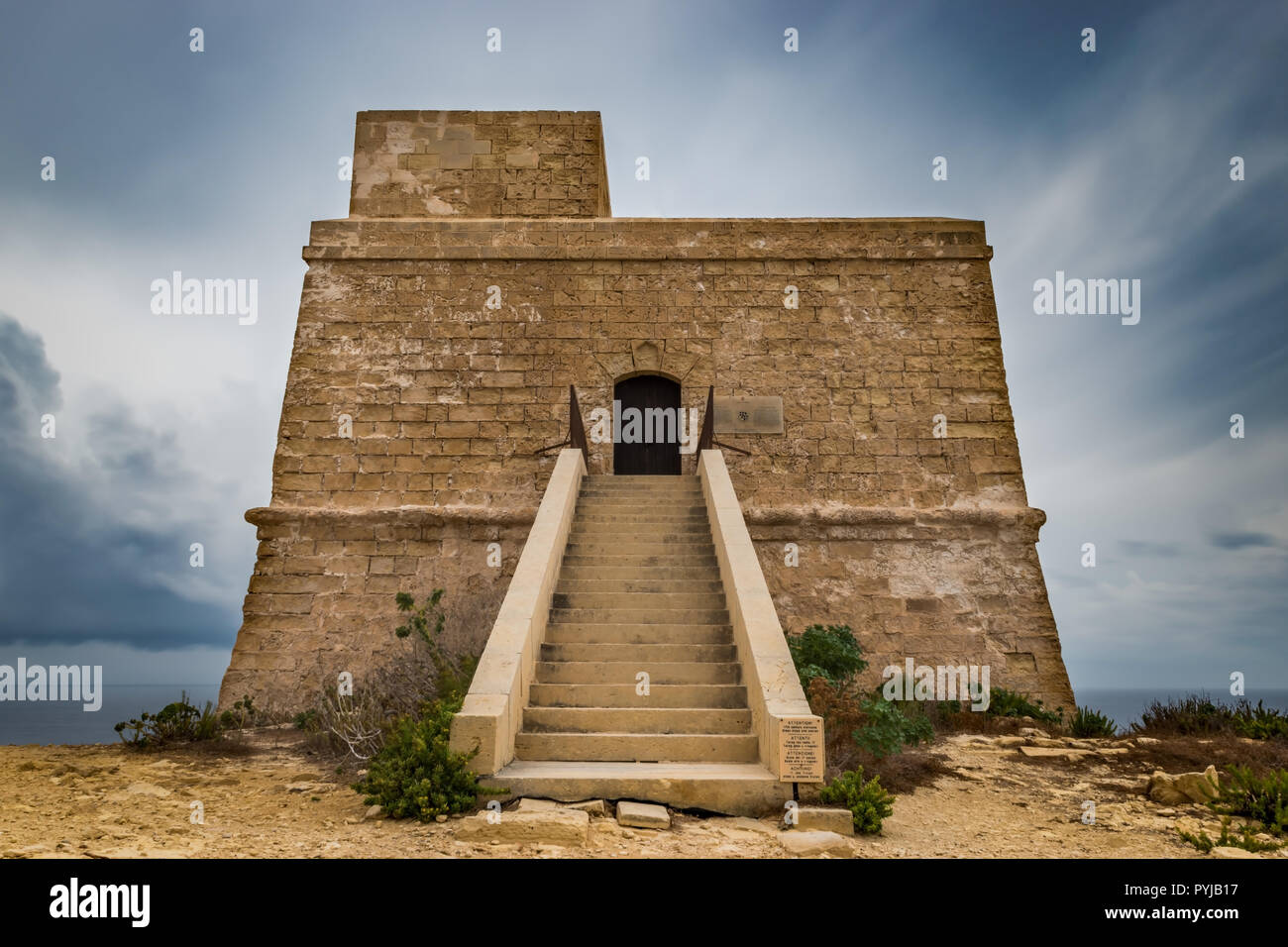 Dwejra bay Tower or watchtower. Qawra. Lascaris towers. Long exposure shot on a bad weather day. Low angel view. Horizontal. Stock Photo