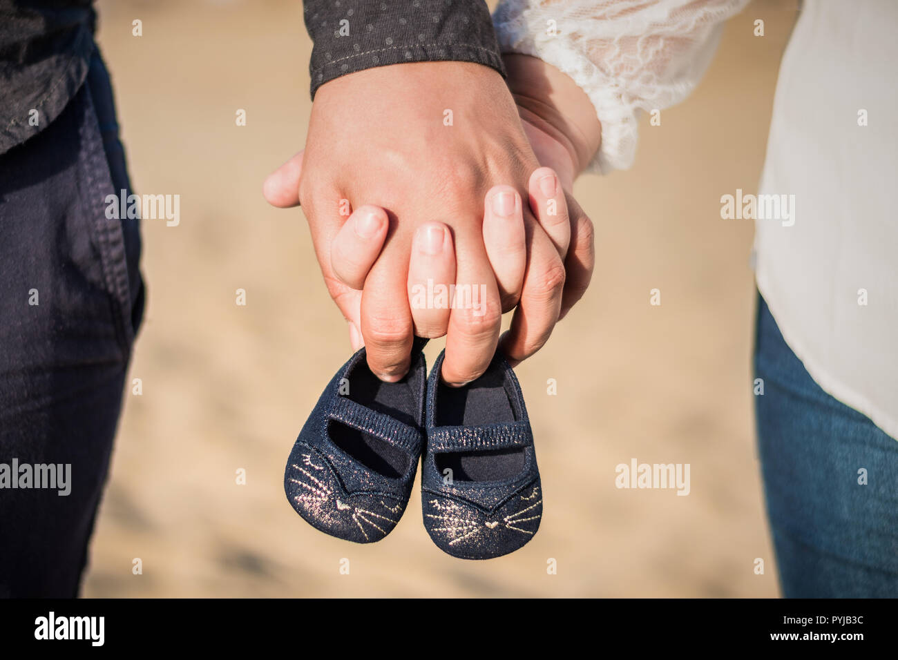 Pregnant woman and man holding baby shoes in hands. Future mom and dad, parents is holding little newborn baby shoes. Birth expectation concept. Waiti Stock Photo