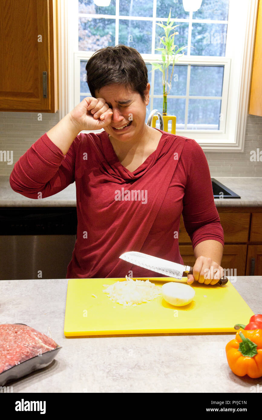 Woman bawling her eyes out while cutting an onion in the kitchen Stock Photo