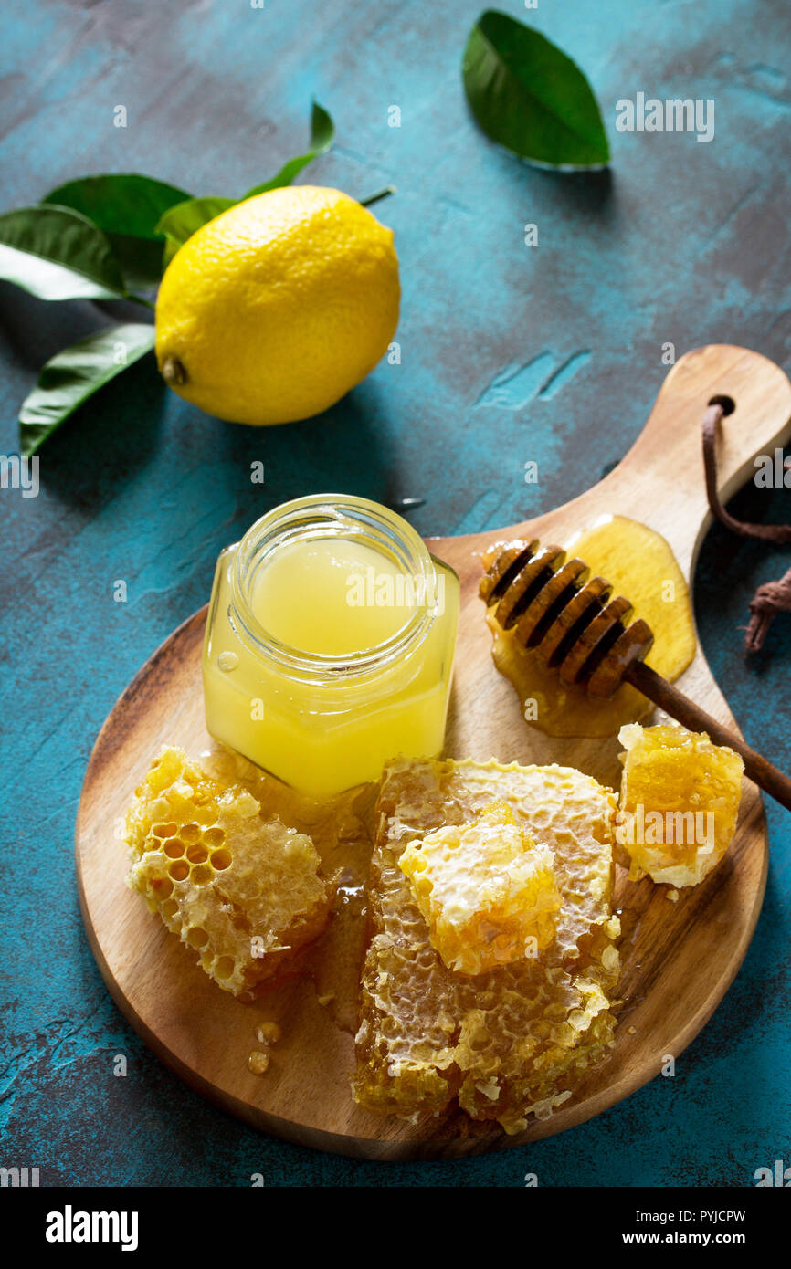 Natural Honey with Lemon. Honey in glass jar and dipper, Sweet Honeycombs on blue stone table. Stock Photo