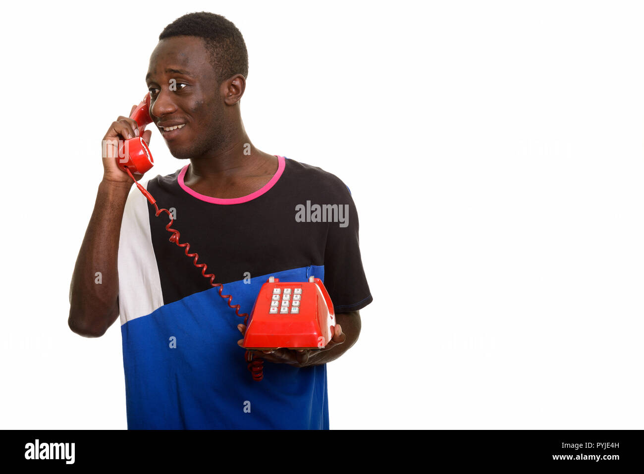 Young happy African man smiling and talking on old telephone Stock Photo