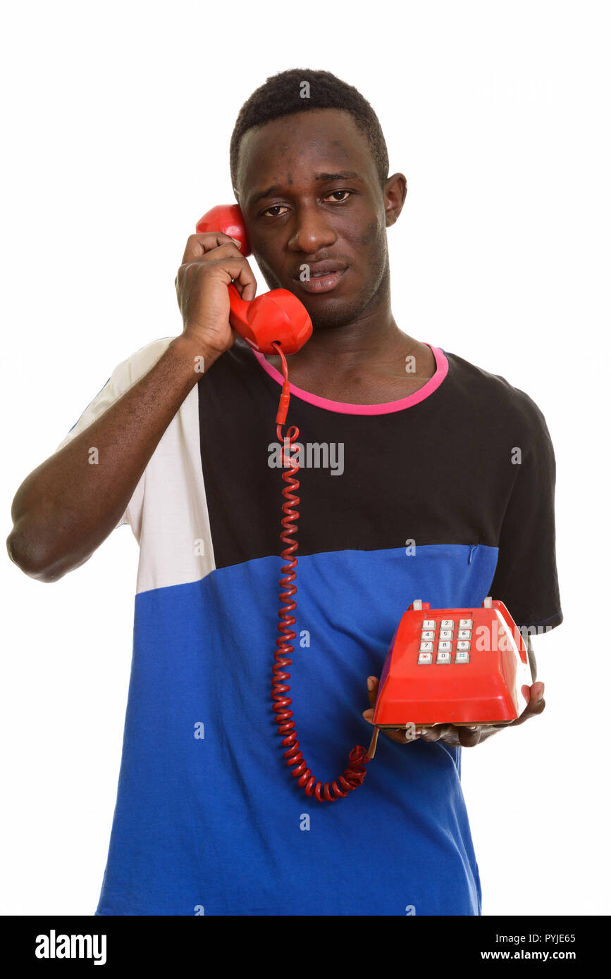 Young African man talking on old telephone looking tired Stock Photo
