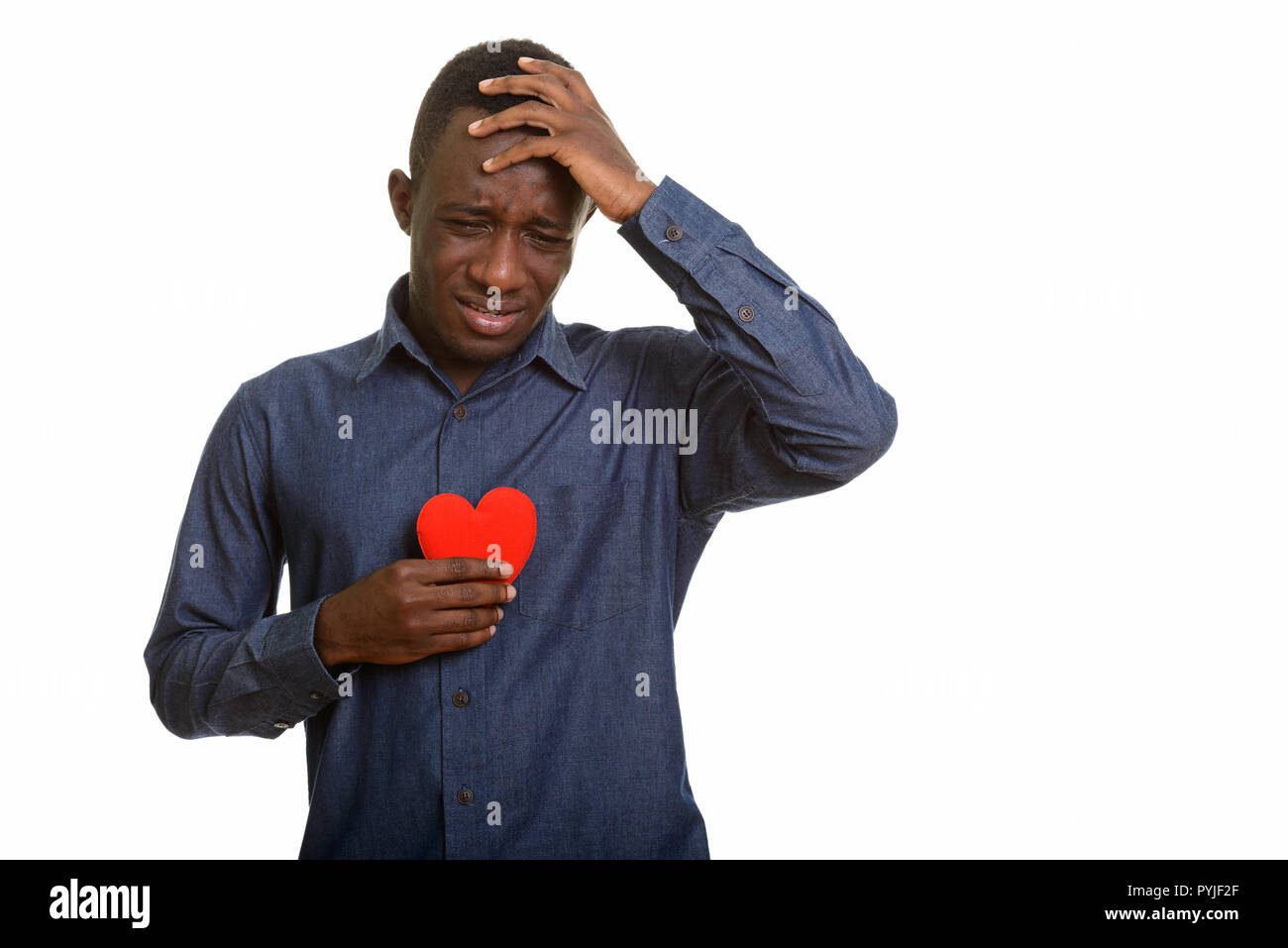 Sad African man crying while holding red heart on chest  Stock Photo