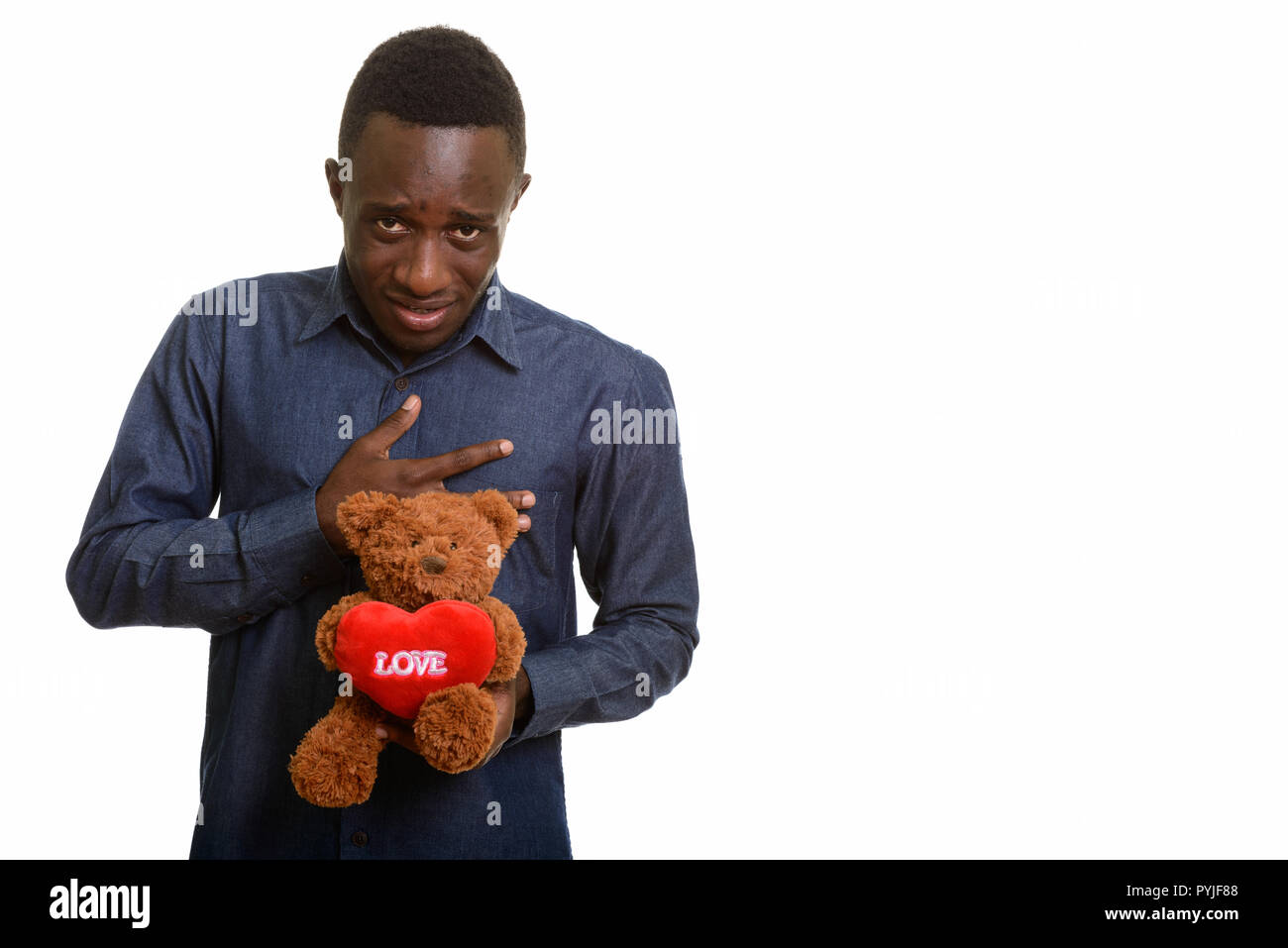 Young African man looking sad while holding teddy bear with hear Stock Photo