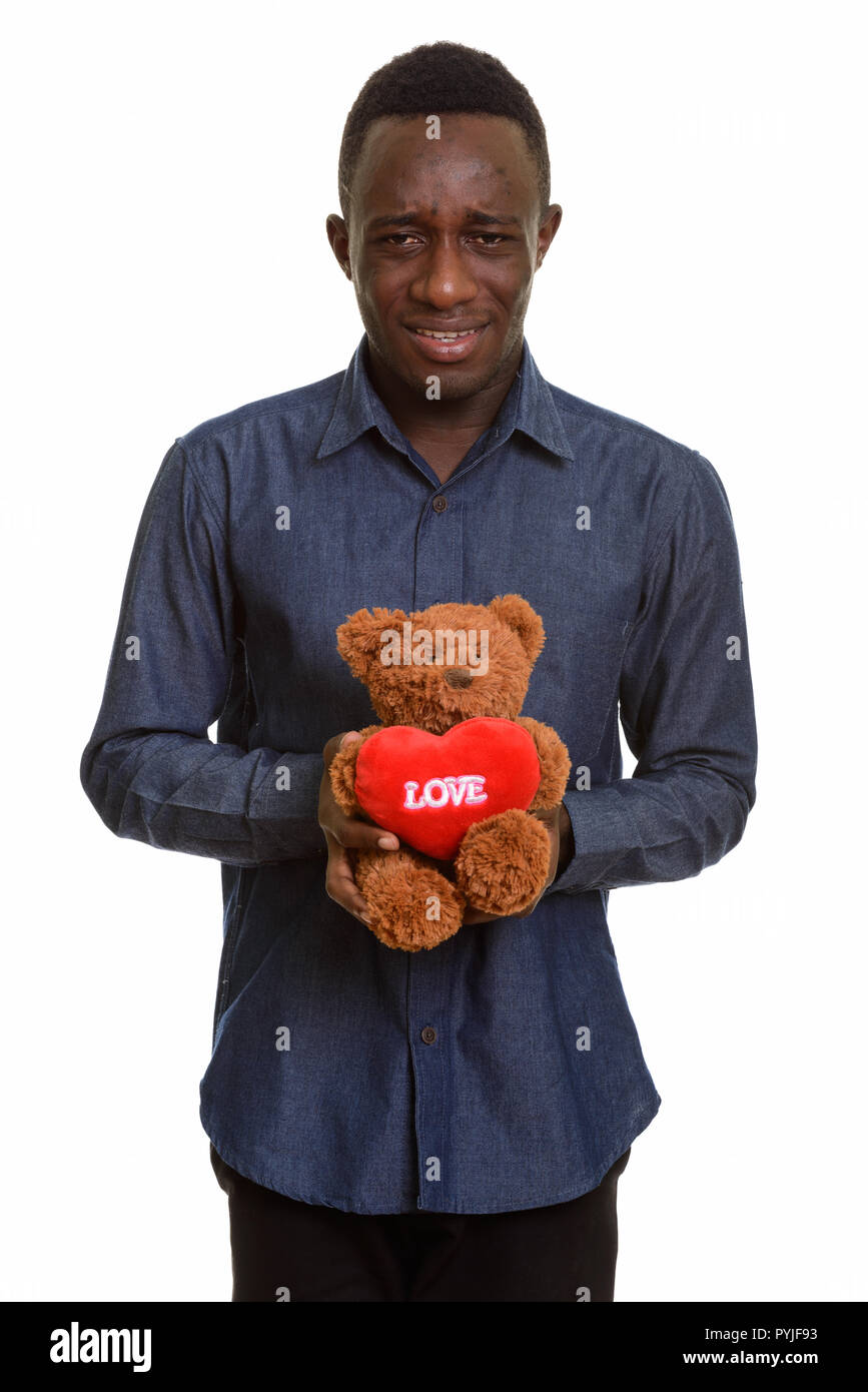 Sad African man holding teddy bear with heart and love sign Stock Photo