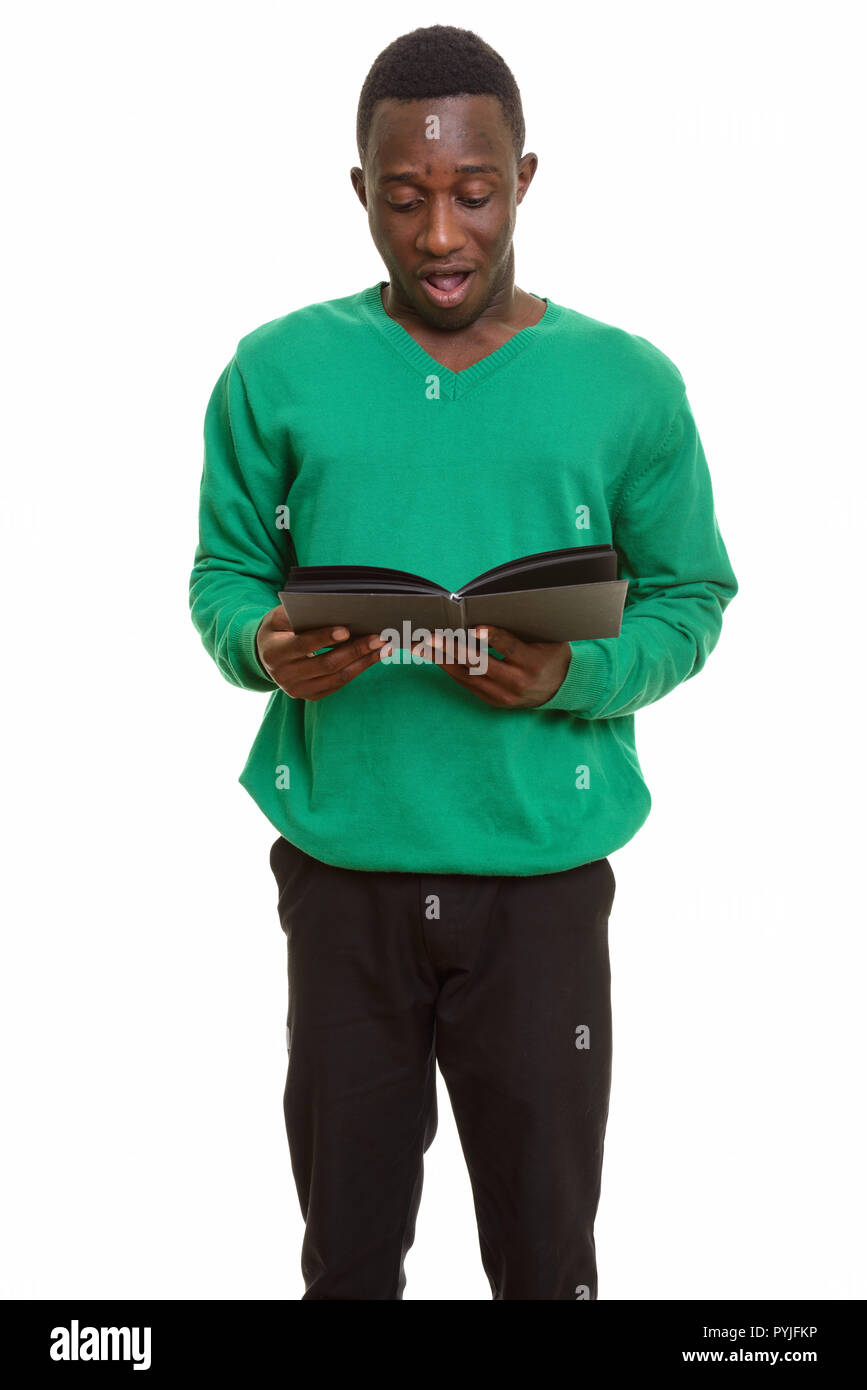 Young handsome African man looking shocked while reading book  Stock Photo