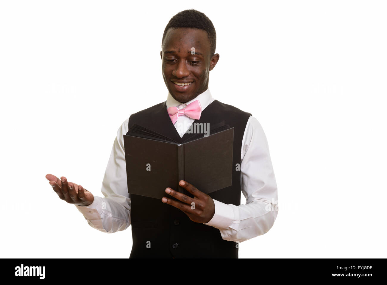 Young happy African waiter smiling and reading book  Stock Photo