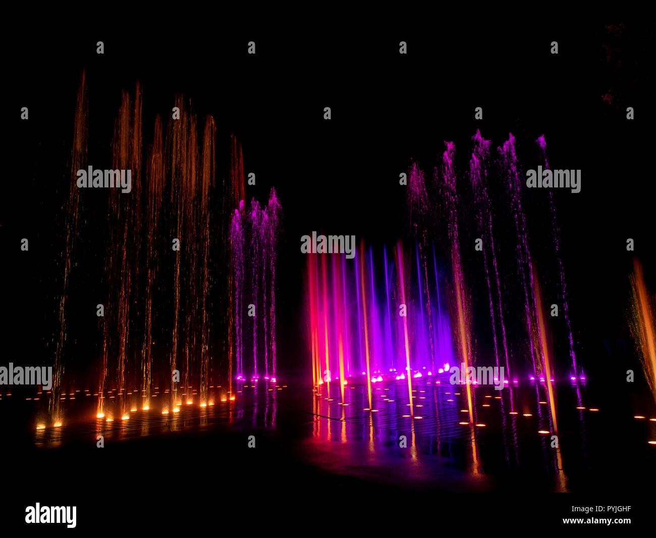 Large multi colored decorative dancing water jet led light fountain show at night Stock Photo
